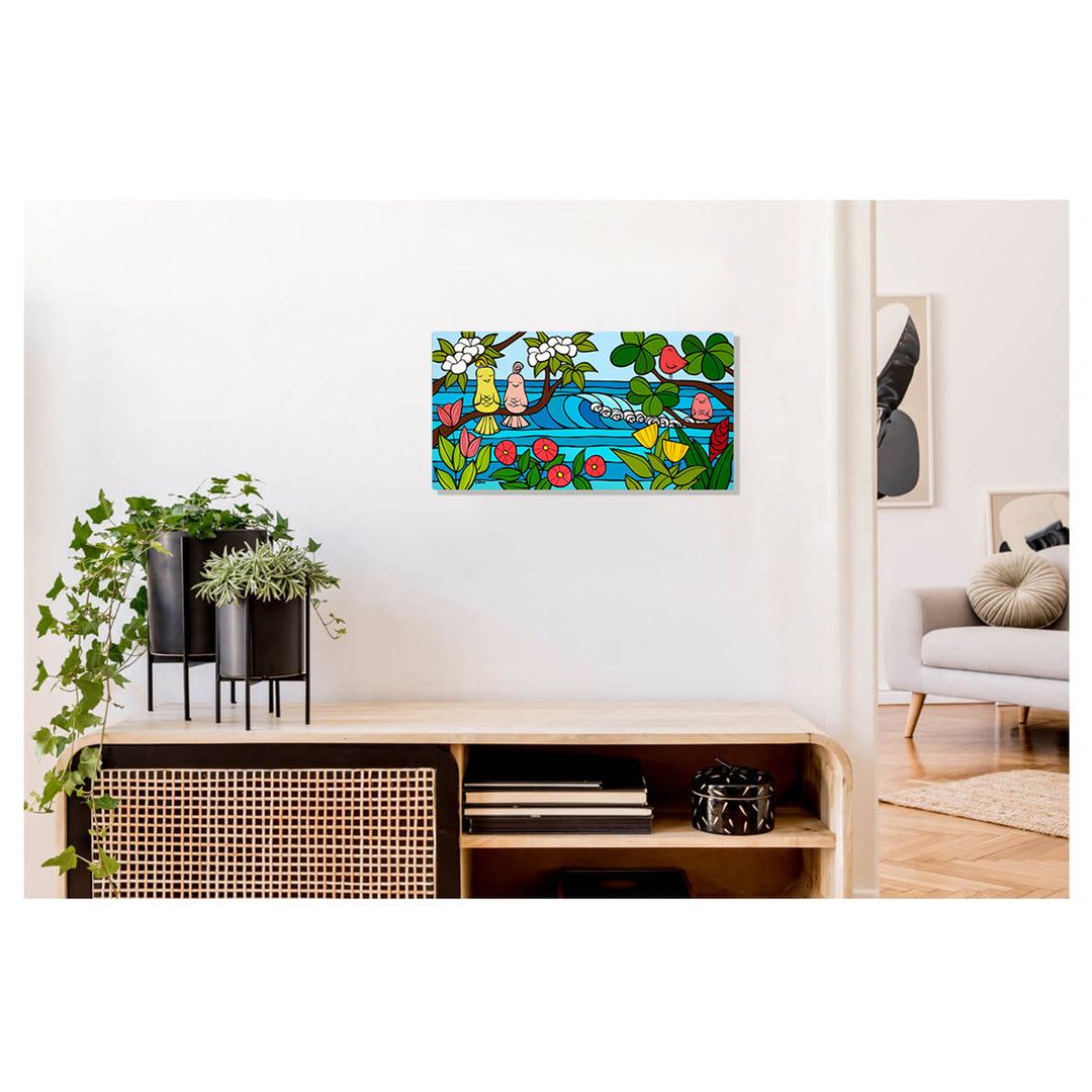 A metal art print featuring some tropical flowers, and colorful birds sitting on tree branches framing distant waves by Hawaii surf artist Heather Brown